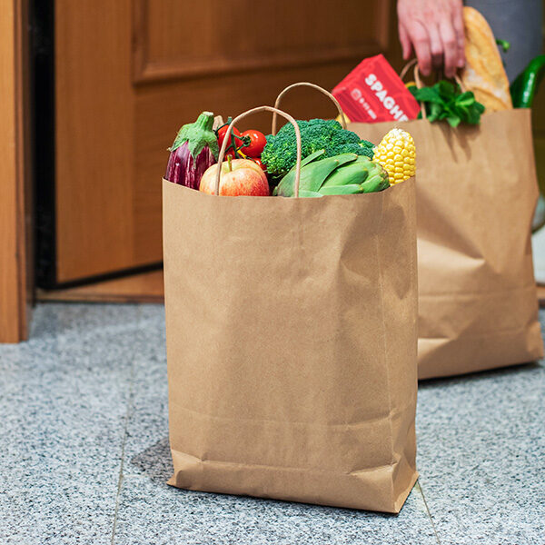 grocery-delivery Two paper bags full of groceries are sitting on the floor, waiting to be put away.